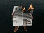 person holding burning newspaper