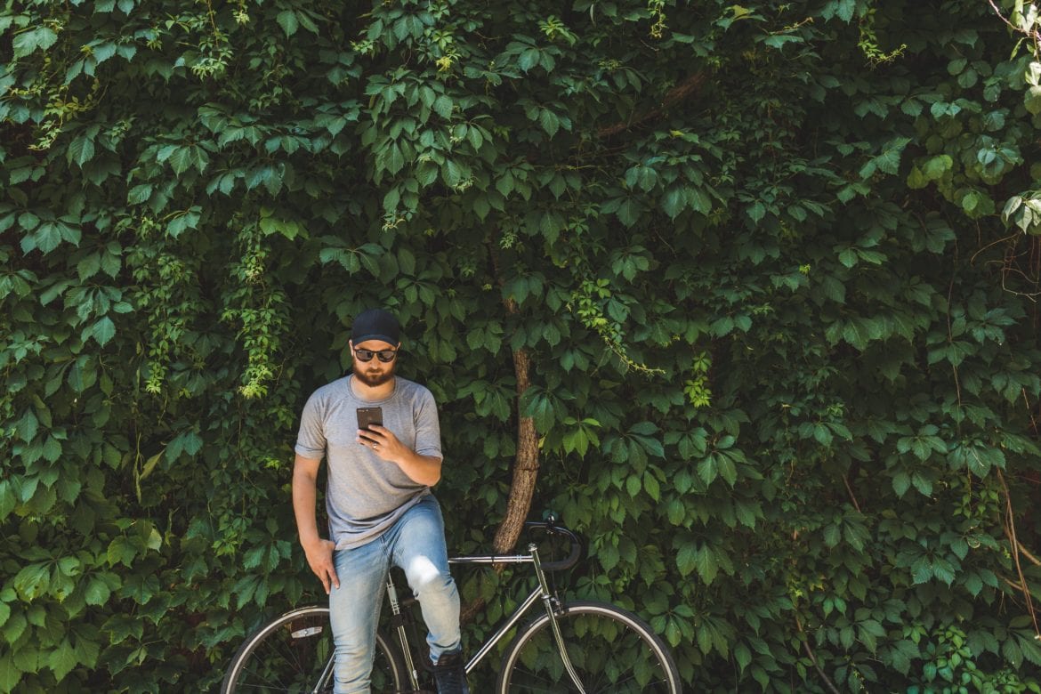 man using phone with bike